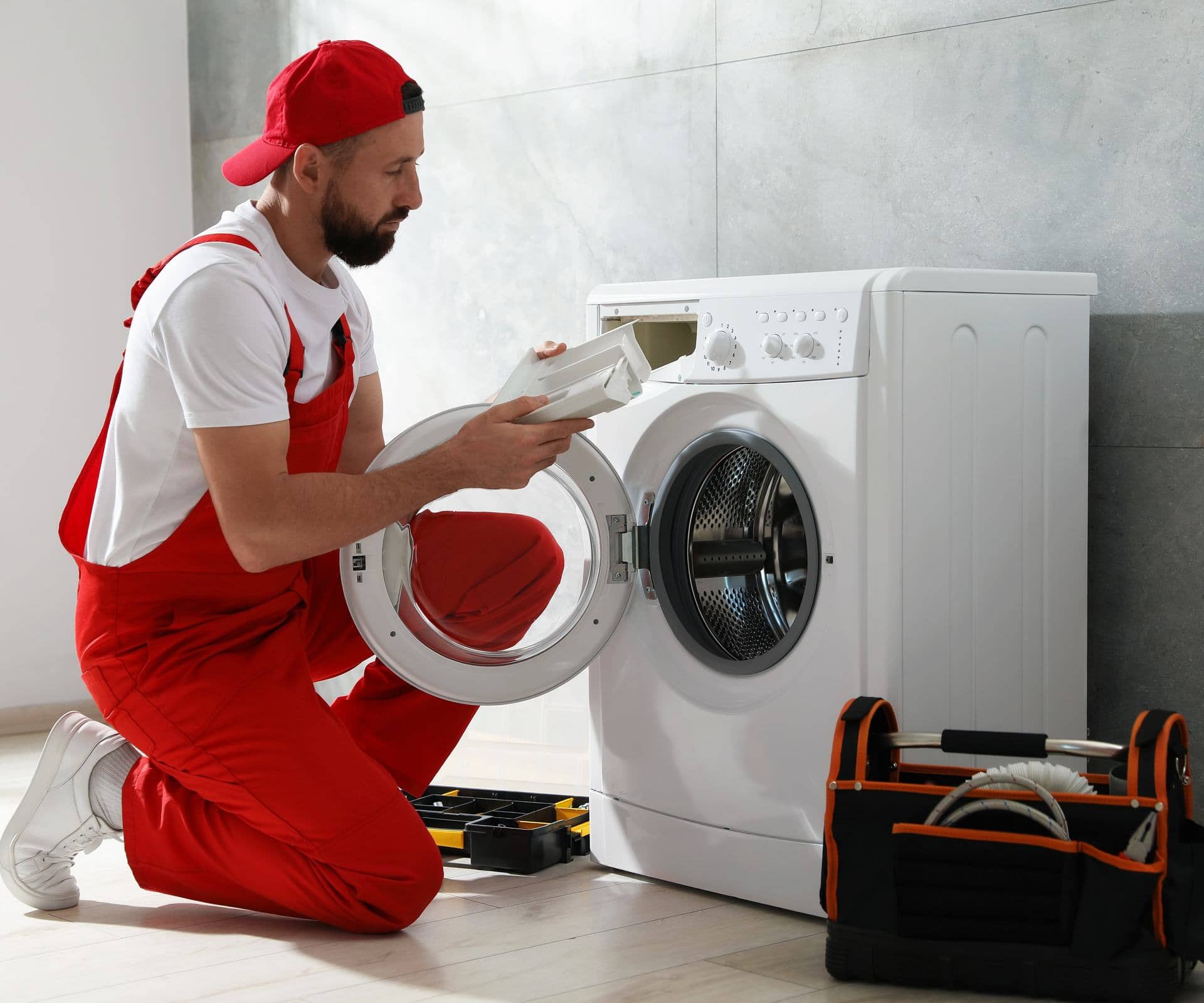 Technician repairing a front-loading washing machine in a Dubai home