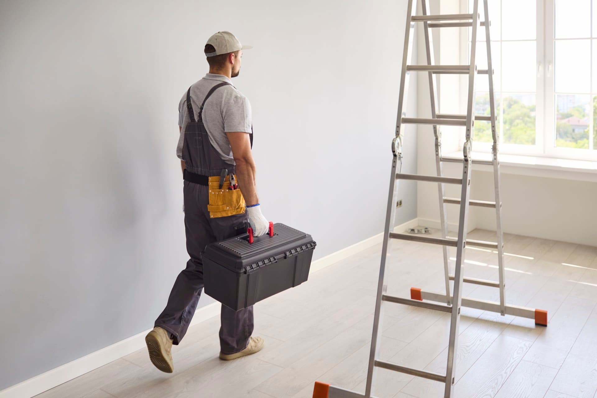 Apartment Maintenance in Dubai: Maintenance technician carrying a toolbox past a ladder in a Dubai apartment