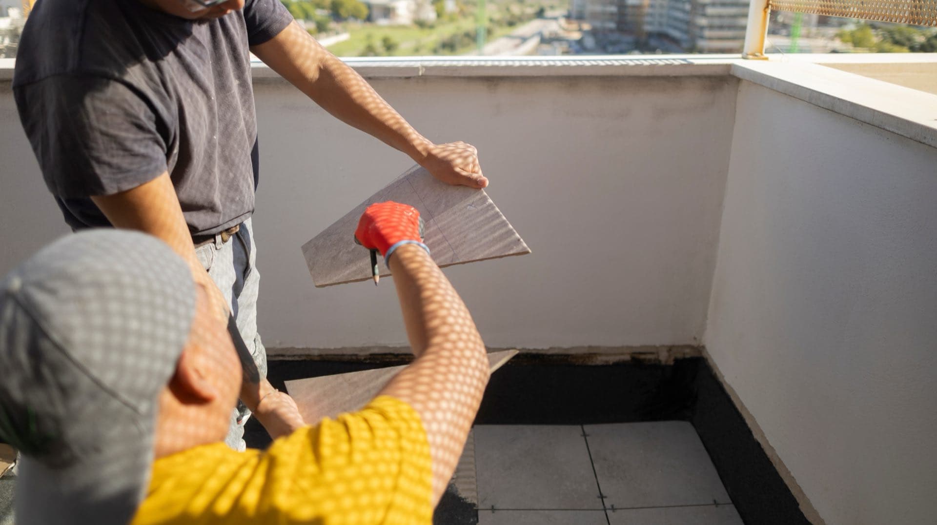 Balcony and Terrace Waterproofing in Dubai: Workers on a balcony with a black waterproof layer turned up at the wall