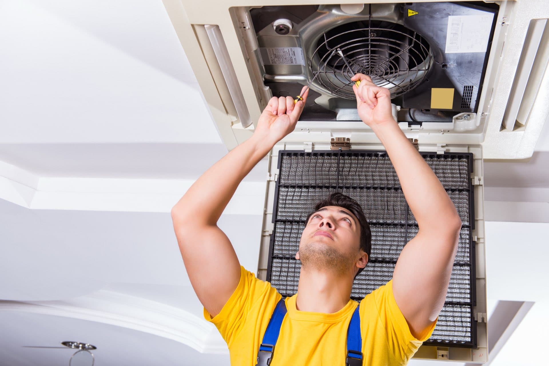 Ducted and Central AC Systems in Dubai: Technician servicing a ceiling AC unit with its filter panel open