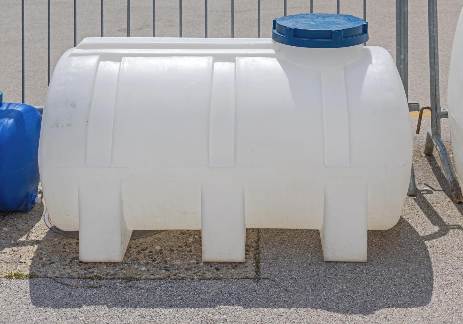 Ground and Underground Water Tank Cleaning in Dubai: Large white plastic water storage tank standing on the ground outdoors