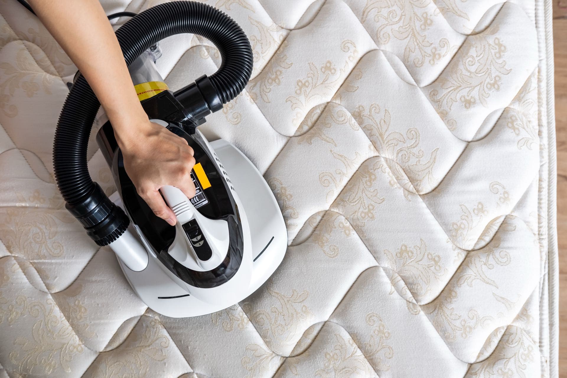 Mattress Cleaning in Dubai: Hand-held vacuum cleaner cleaning the surface of a mattress