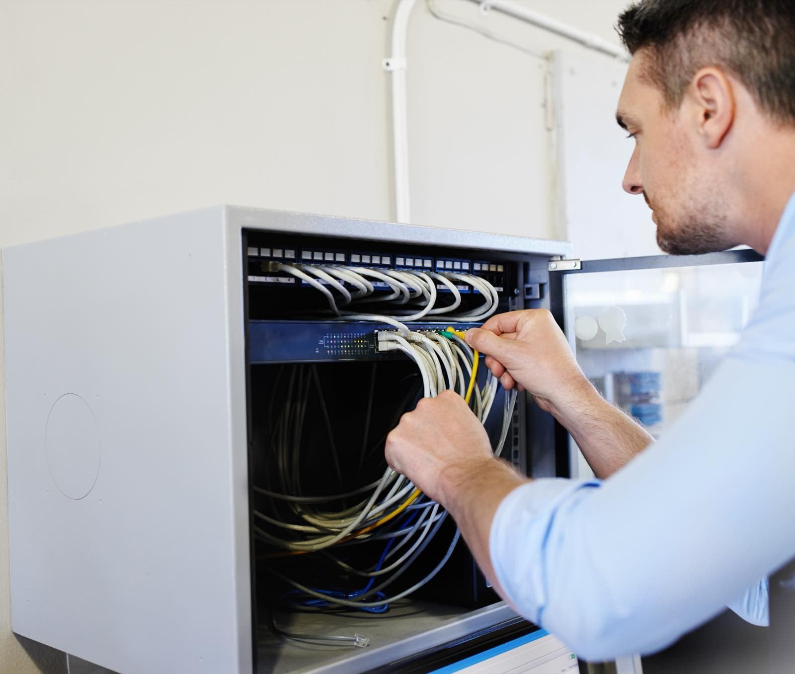 Workspace and IT Equipment Care in Dubai: Technician connecting network cables in a cabinet