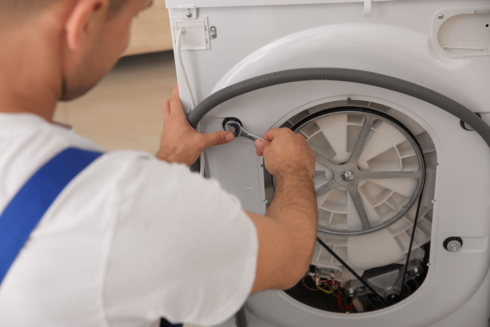 Washing Machine Repair in Dubai: Technician checking the drum and belt of a washing machine with a spanner