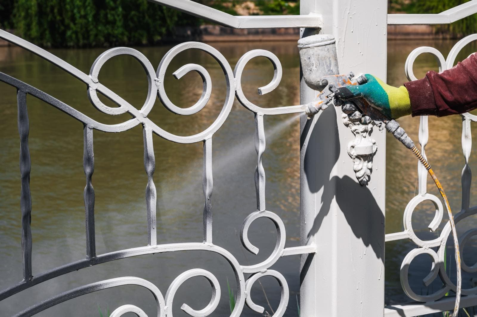 Railing and Metalwork Spraying in Dubai: Worker spraying white paint on an ornamental metal railing