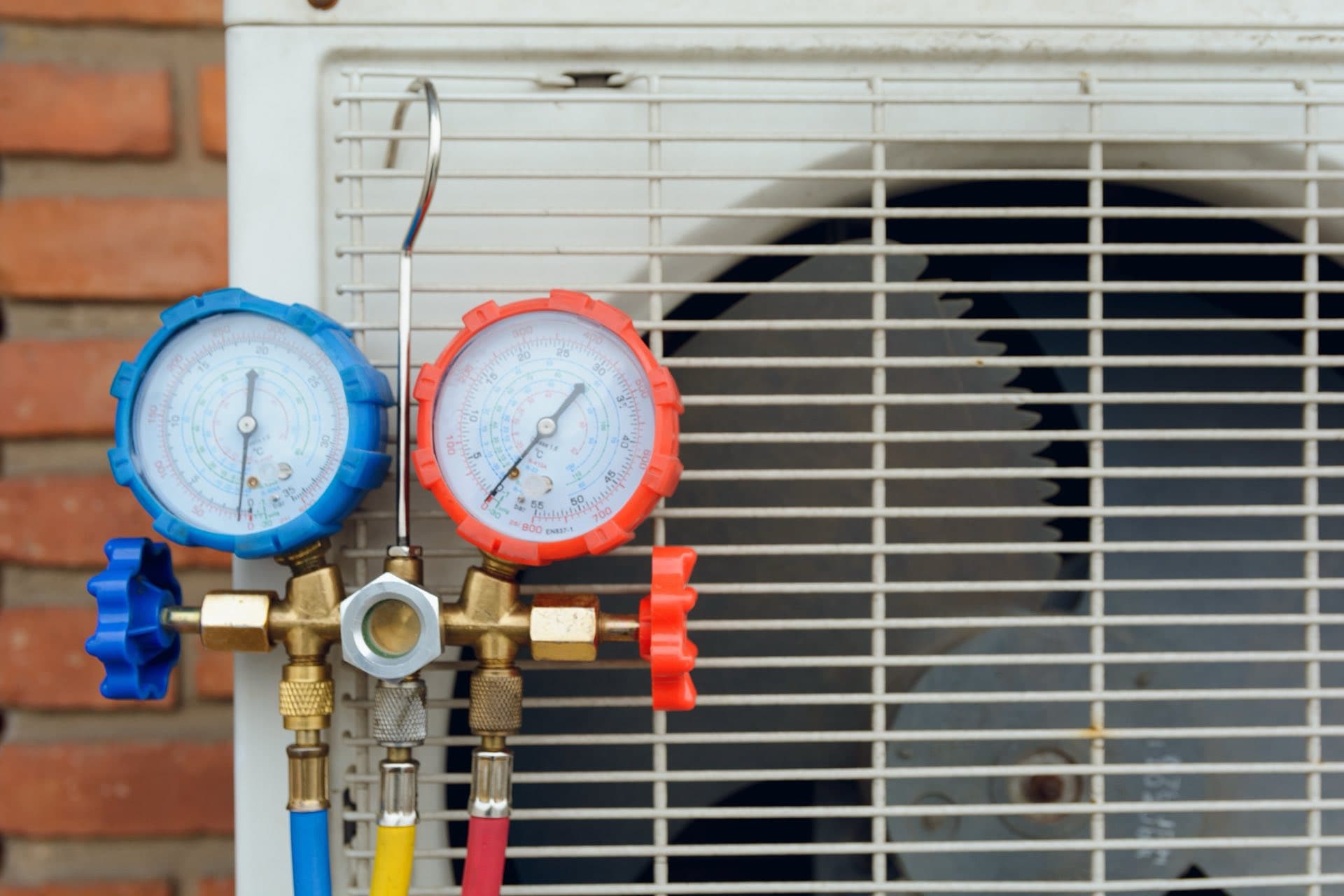 AC Gas Refilling in Dubai: Refrigerant pressure gauges connected to an outdoor AC unit