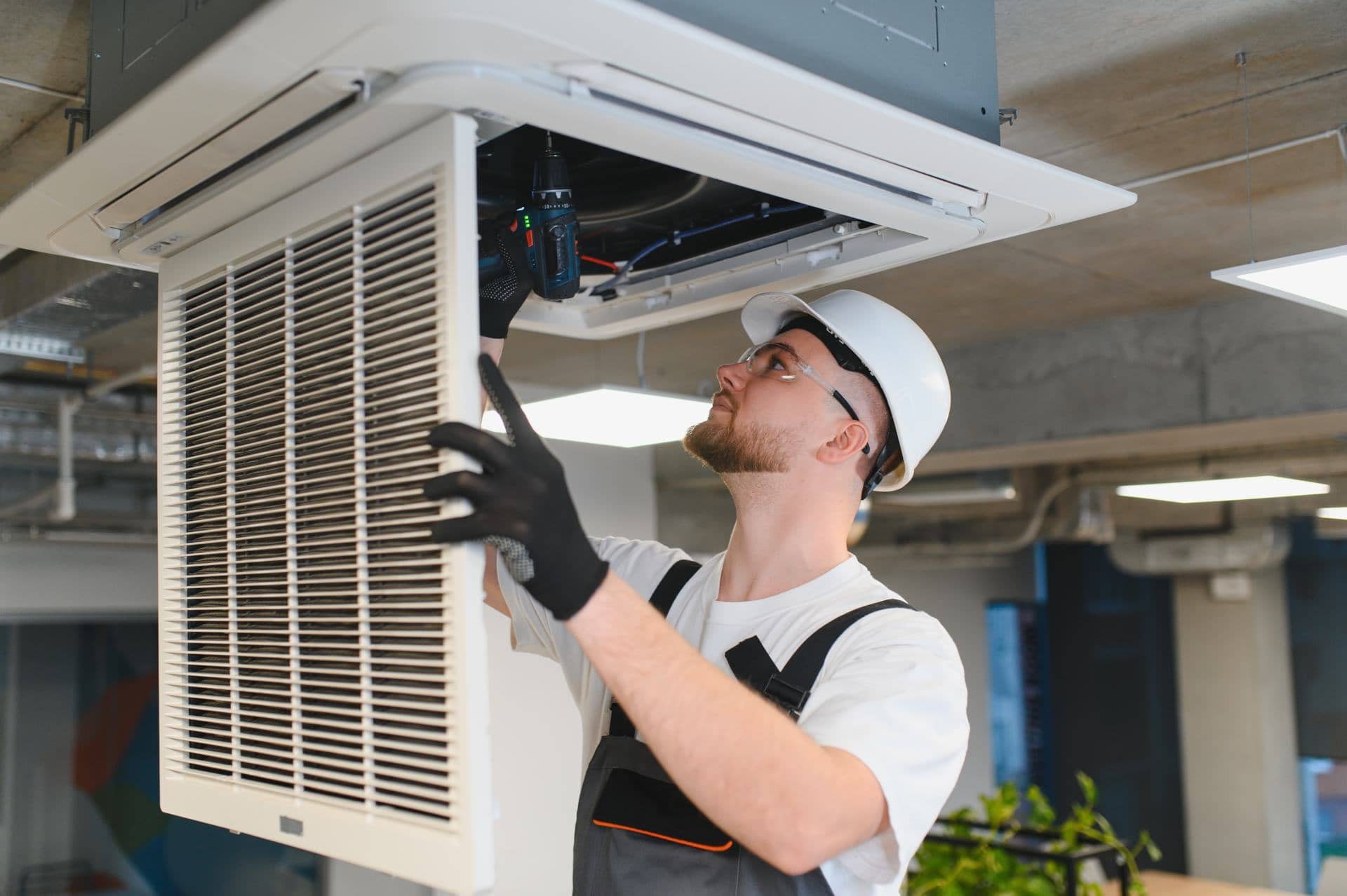 AC technician servicing a ceiling cassette air conditioner in Dubai
