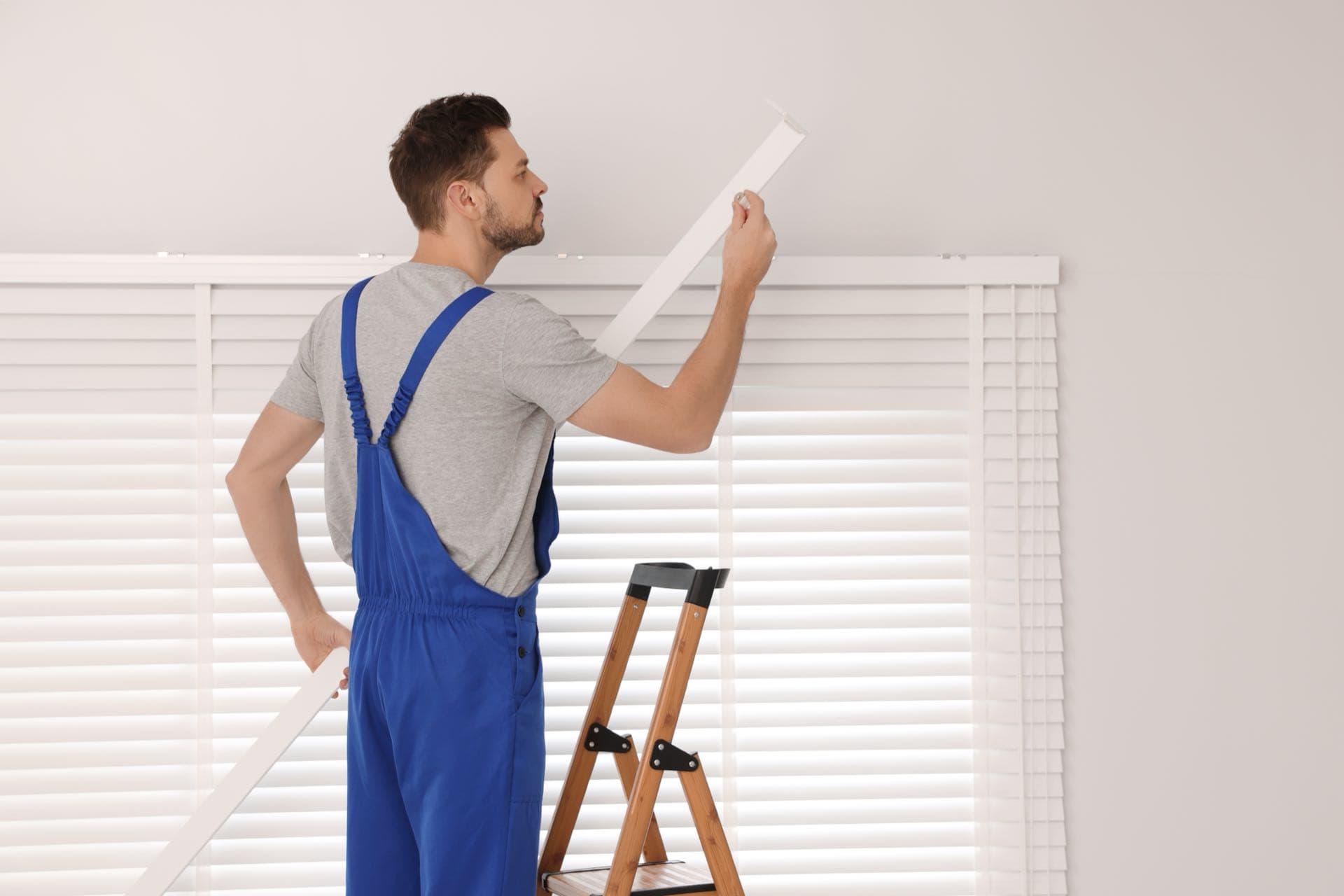 Blinds Installation in Dubai: Installer on a stepladder fitting a window blind in a Dubai apartment
