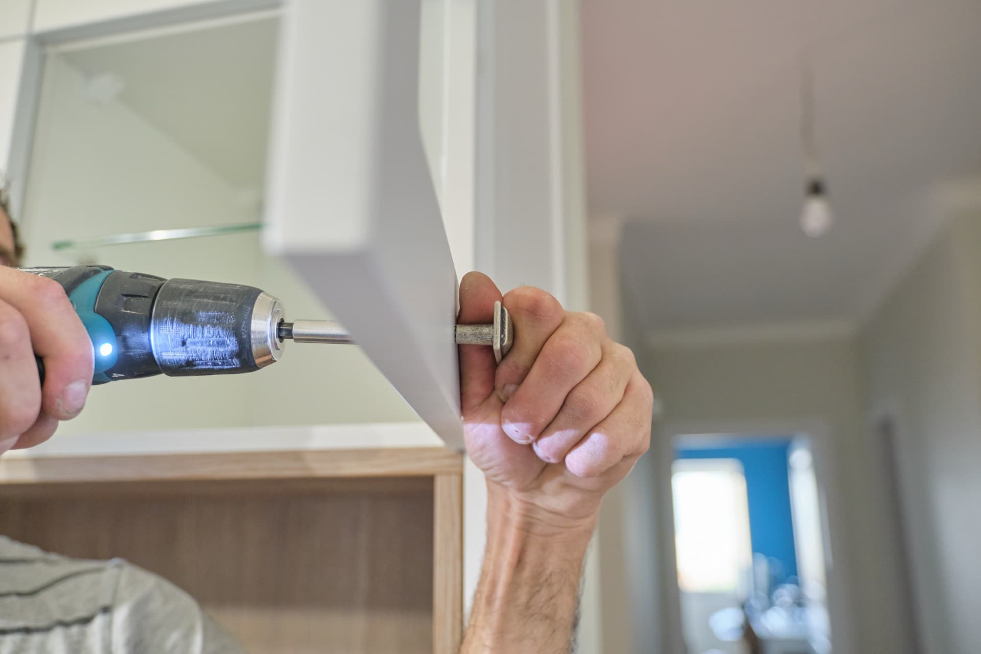 Fittings and Small Repairs in Dubai: Carpenter drilling a fixing into a cabinet door in a Dubai home