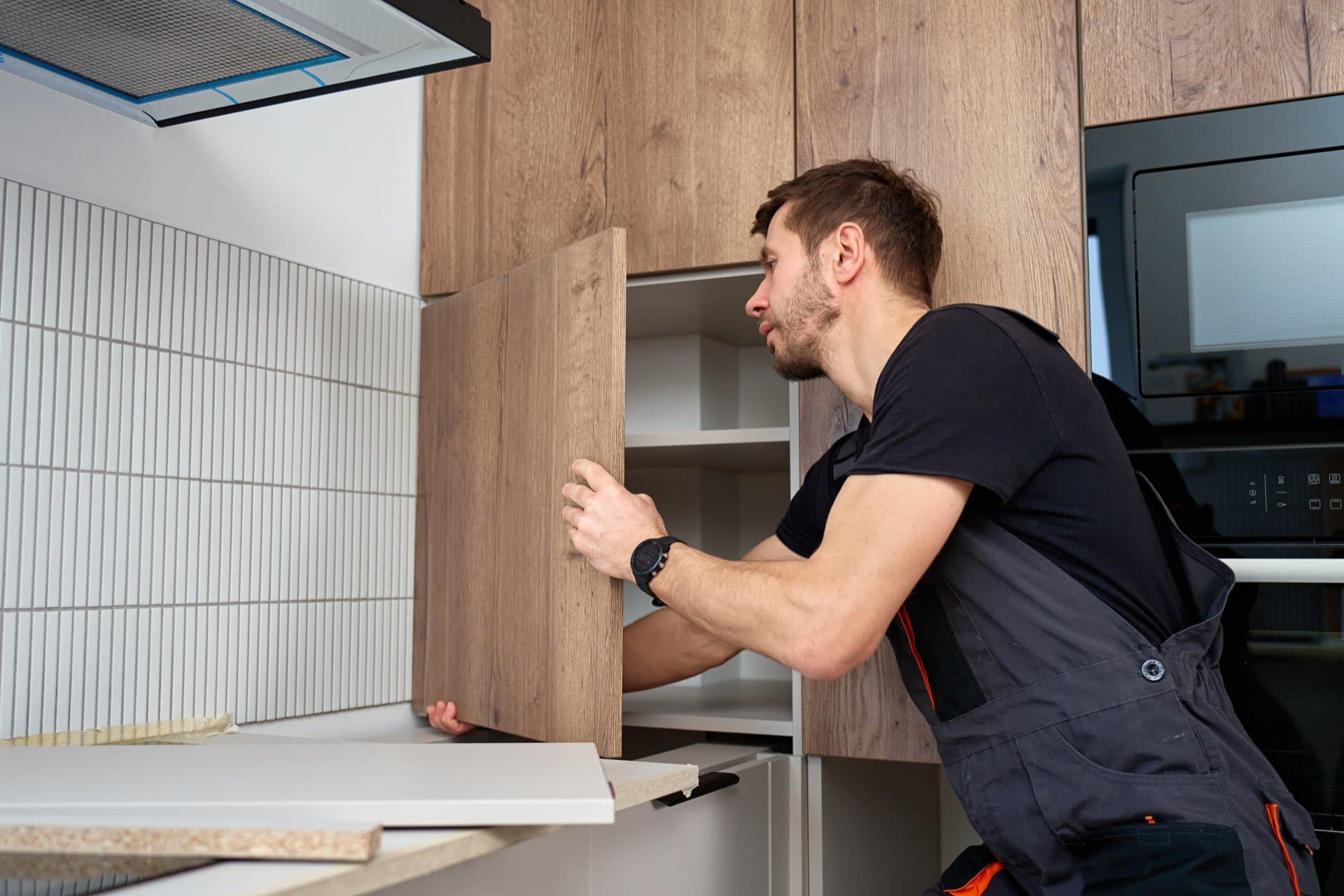 Door Repair and Adjustment in Dubai: Carpenter fitting a wooden cabinet door in a new kitchen in Dubai