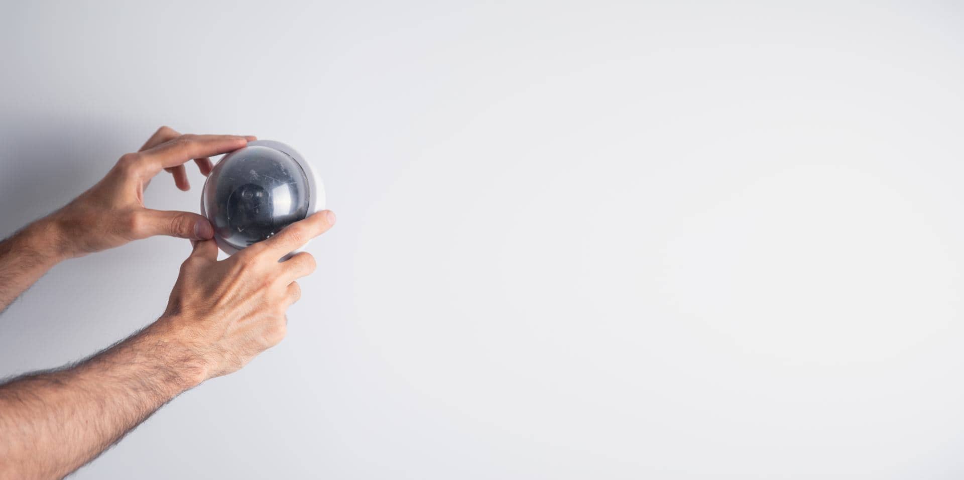 Hands fitting a dome CCTV security camera on a wall in Dubai