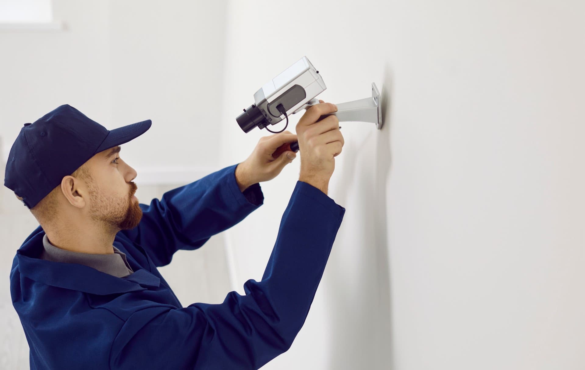 CCTV Repair in Dubai: Technician repairing a CCTV camera mounted on a wall in Dubai