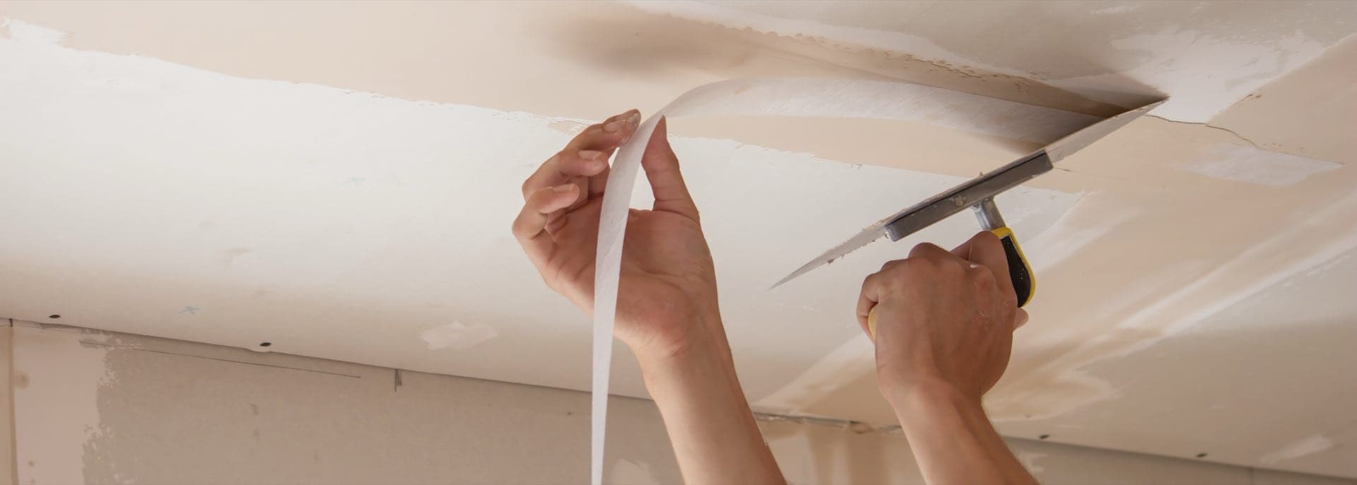 Ceiling Repair After Leaks in Dubai: Plasterer patching and smoothing a damaged ceiling