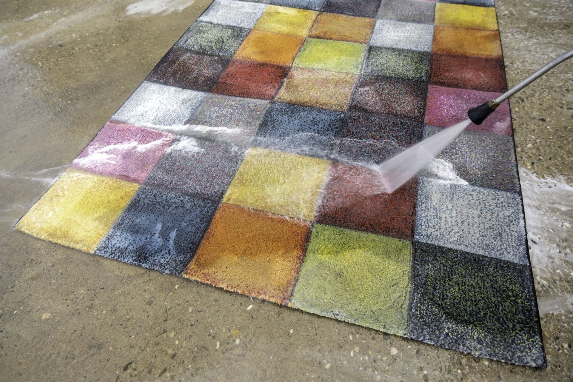 Carpet and Rug Cleaning in Dubai: Colourful rug being rinsed with a water jet