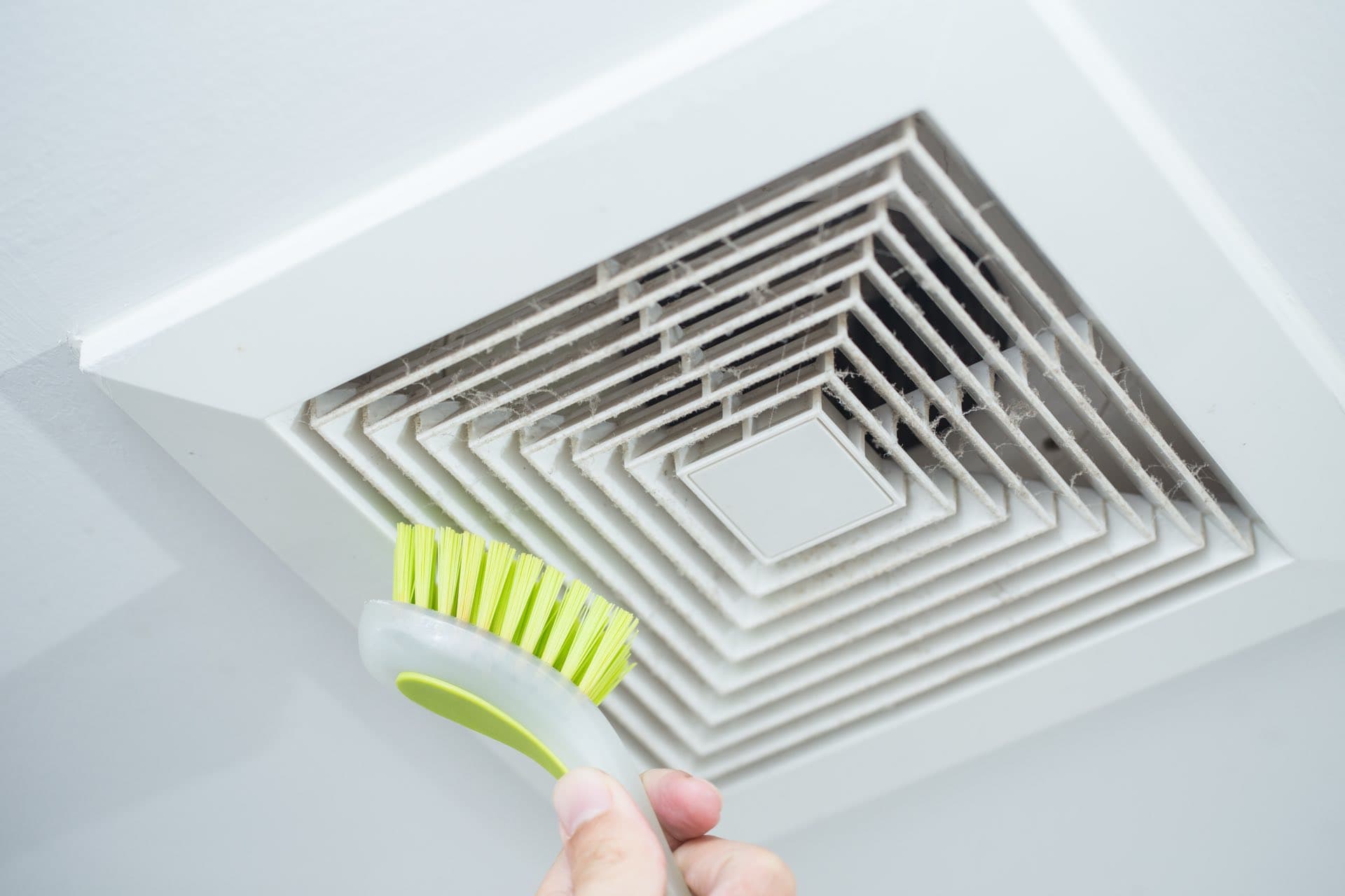 AC Diffuser and Grille Cleaning in Dubai: Cleaning a dusty ceiling AC vent with a brush