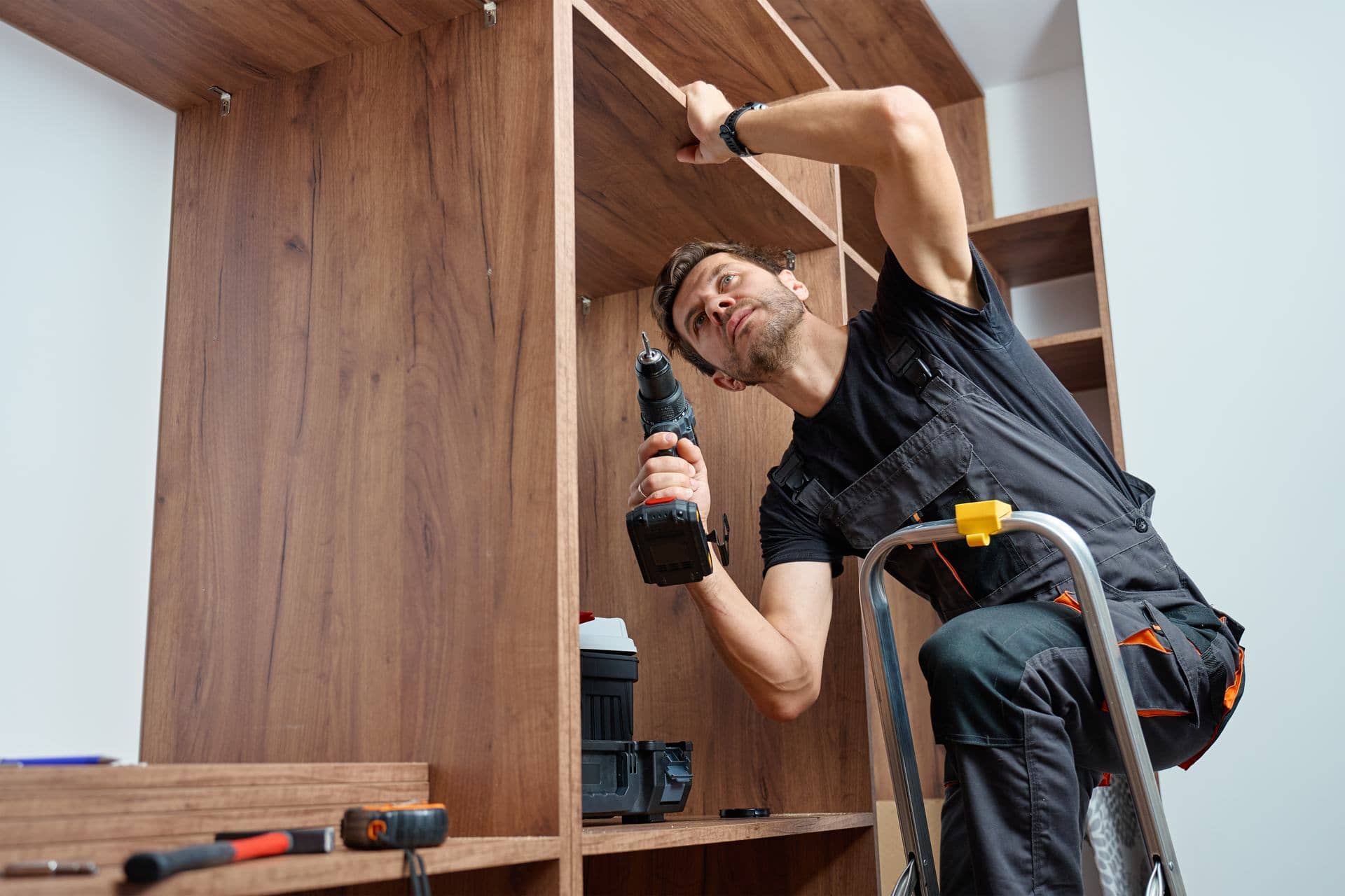 Technician assembling and fixing a fitted wardrobe with a drill in Dubai