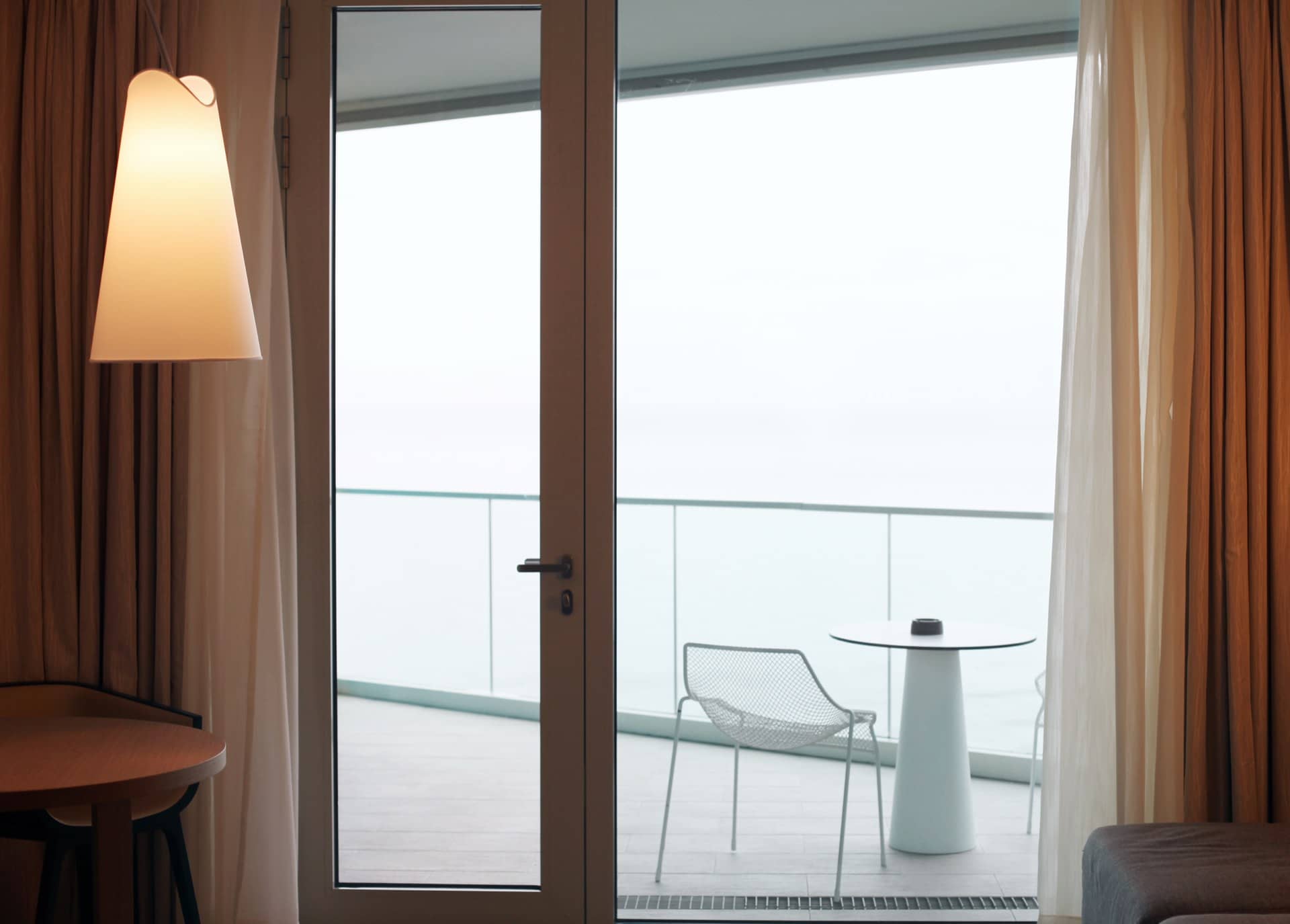 Holiday apartment living room with a glass door opening onto a sea-view balcony