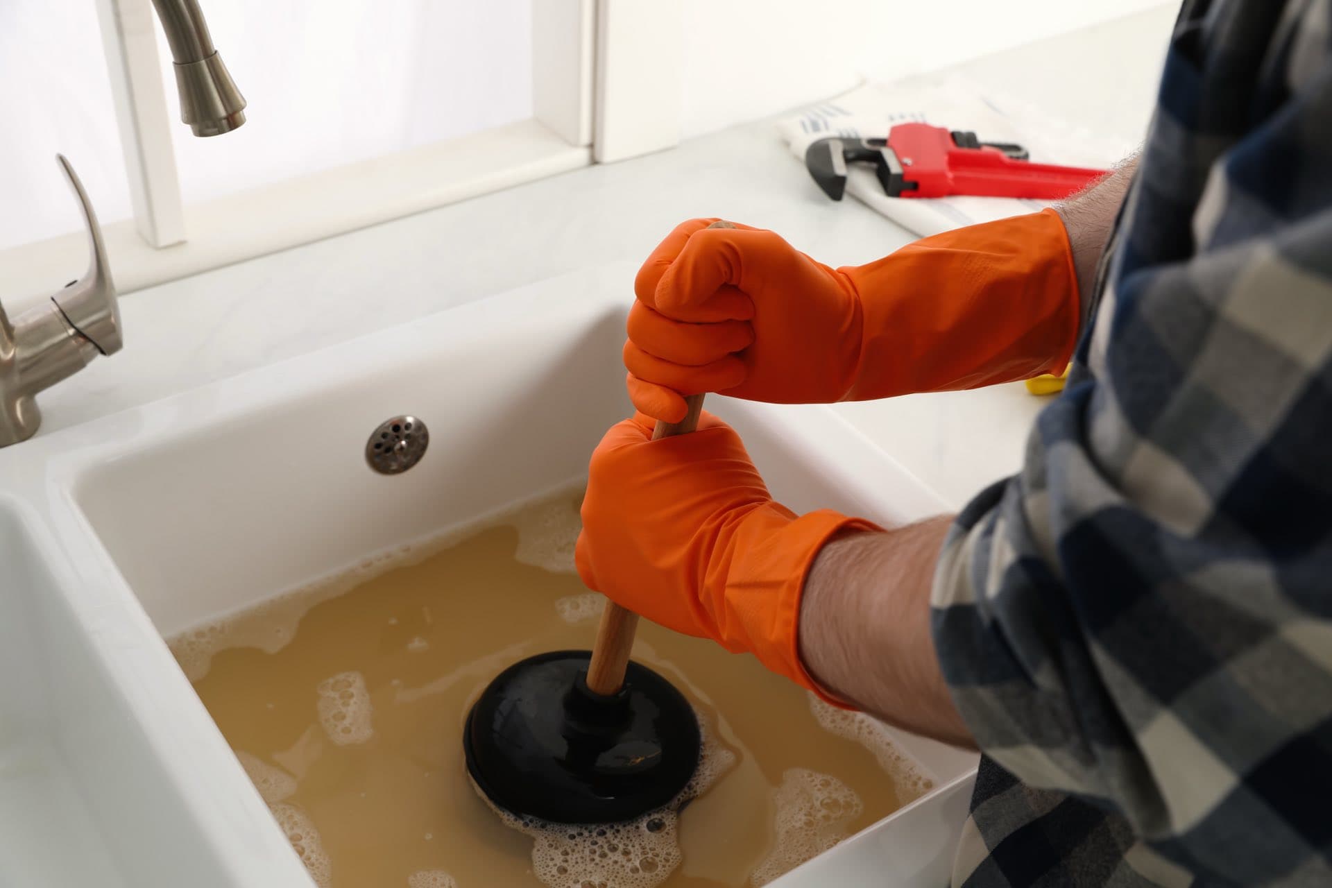 Kitchen Sink Unblocking in Dubai: Gloved hands unblocking a kitchen sink with a plunger