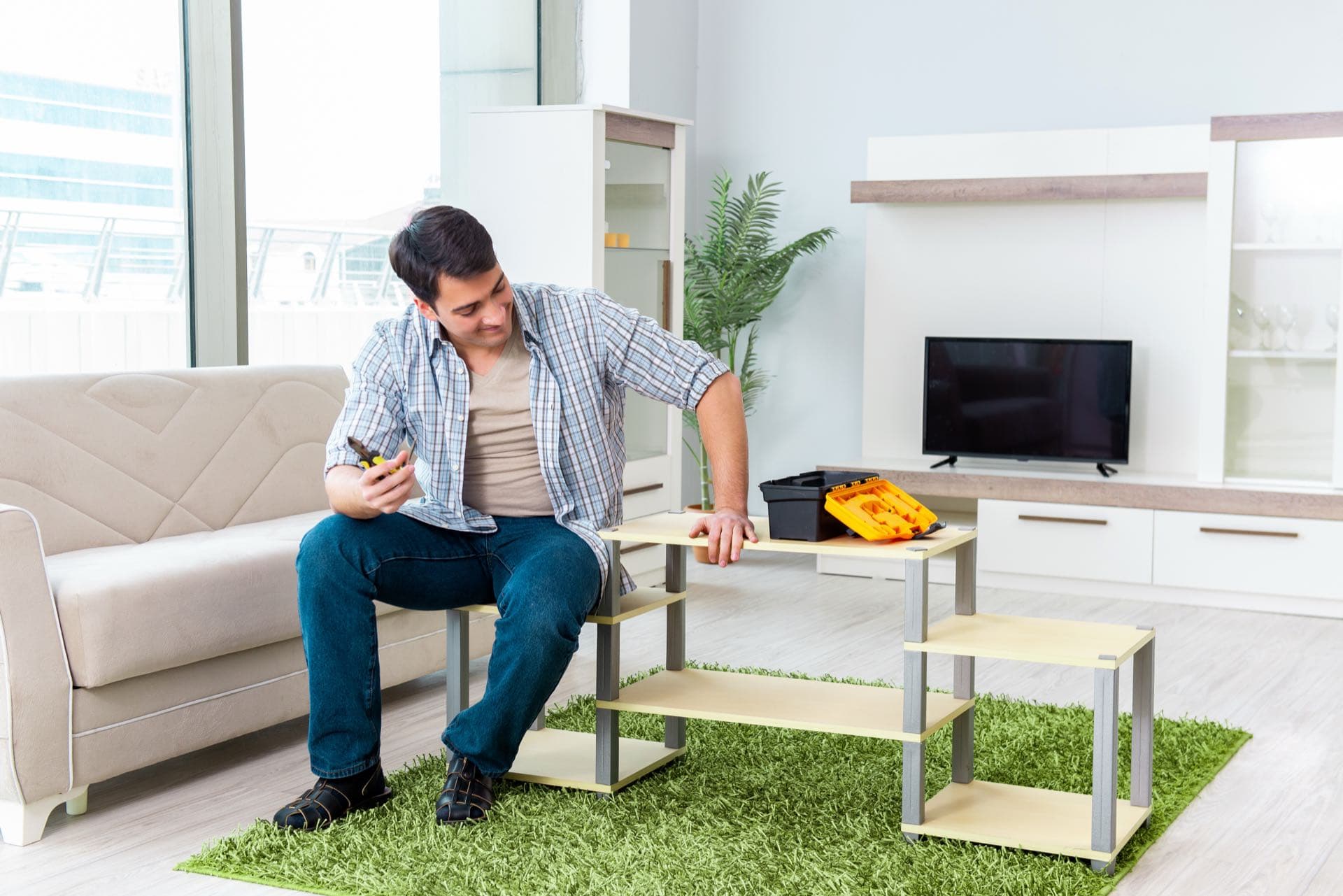 Shelving and TV Unit Assembly in Dubai: Man assembling a TV stand in a living room