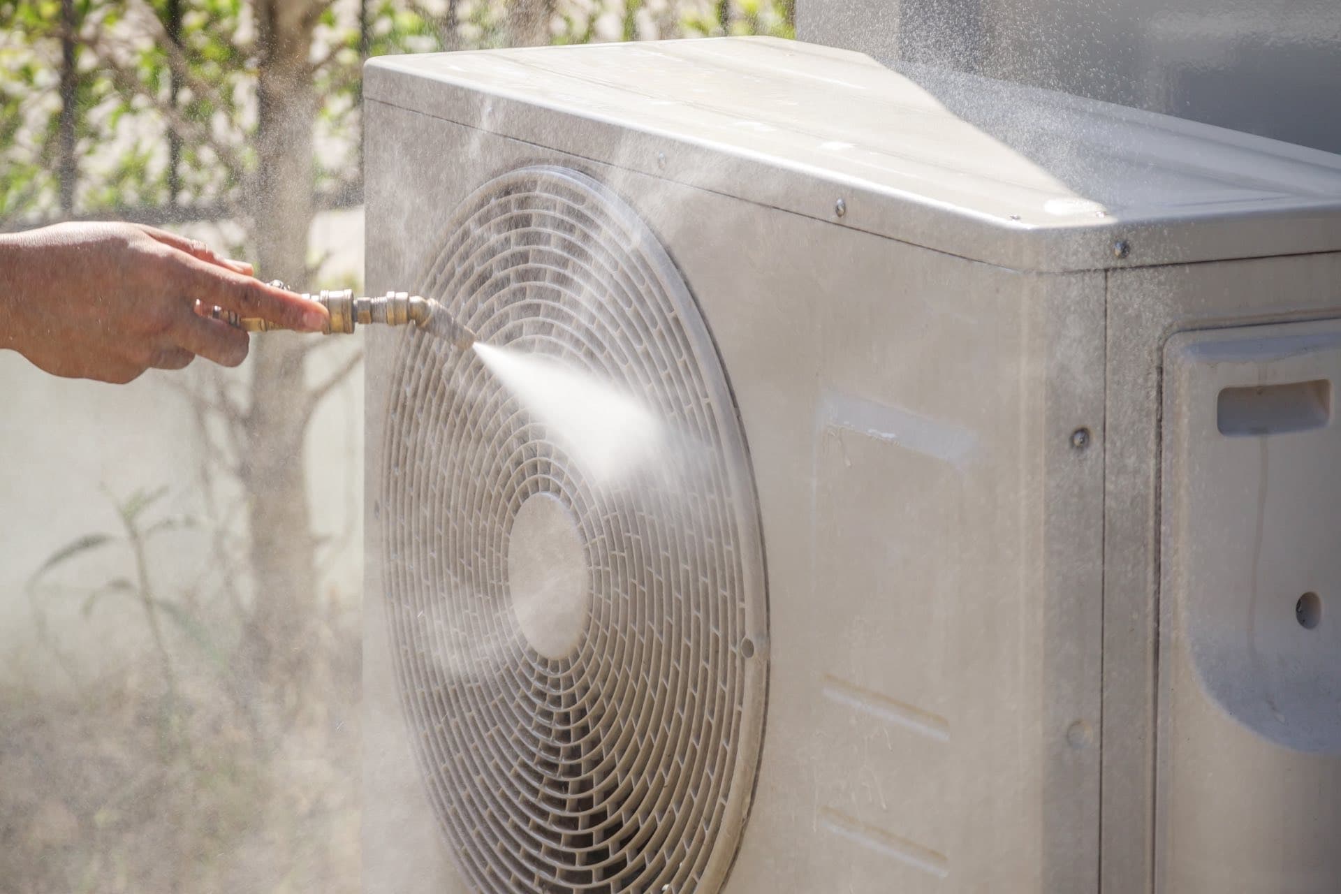 Outdoor AC Unit Cleaning in Dubai: Water spray cleaning the fan and coil of an outdoor AC unit