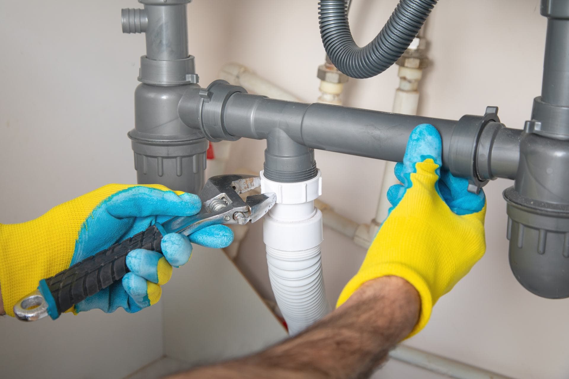 Small Plumbing Fixes in Dubai: Plumber tightening a leaking drain pipe joint during leak detection in Dubai