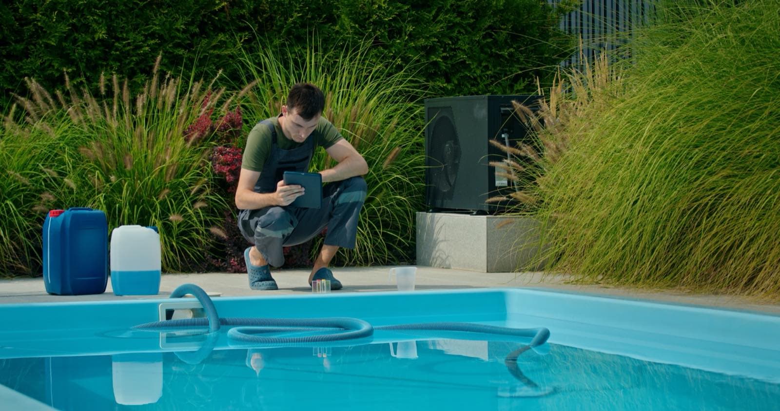 Regular Villa Pool Care in Dubai: Pool technician in a green shirt working at the edge of a garden pool
