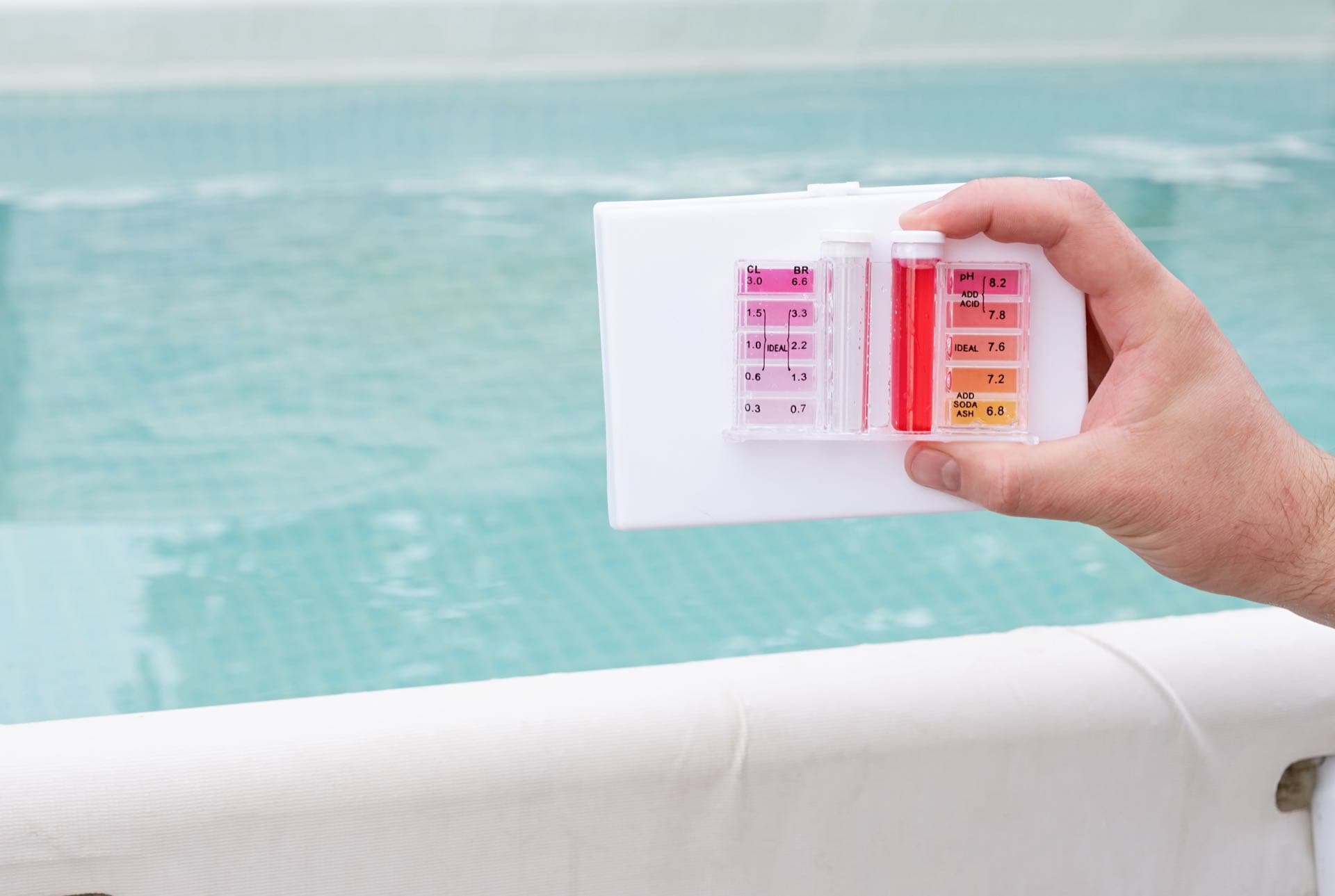Pool Water Testing and Balancing in Dubai: Hand holding a pH and chlorine test kit beside a swimming pool