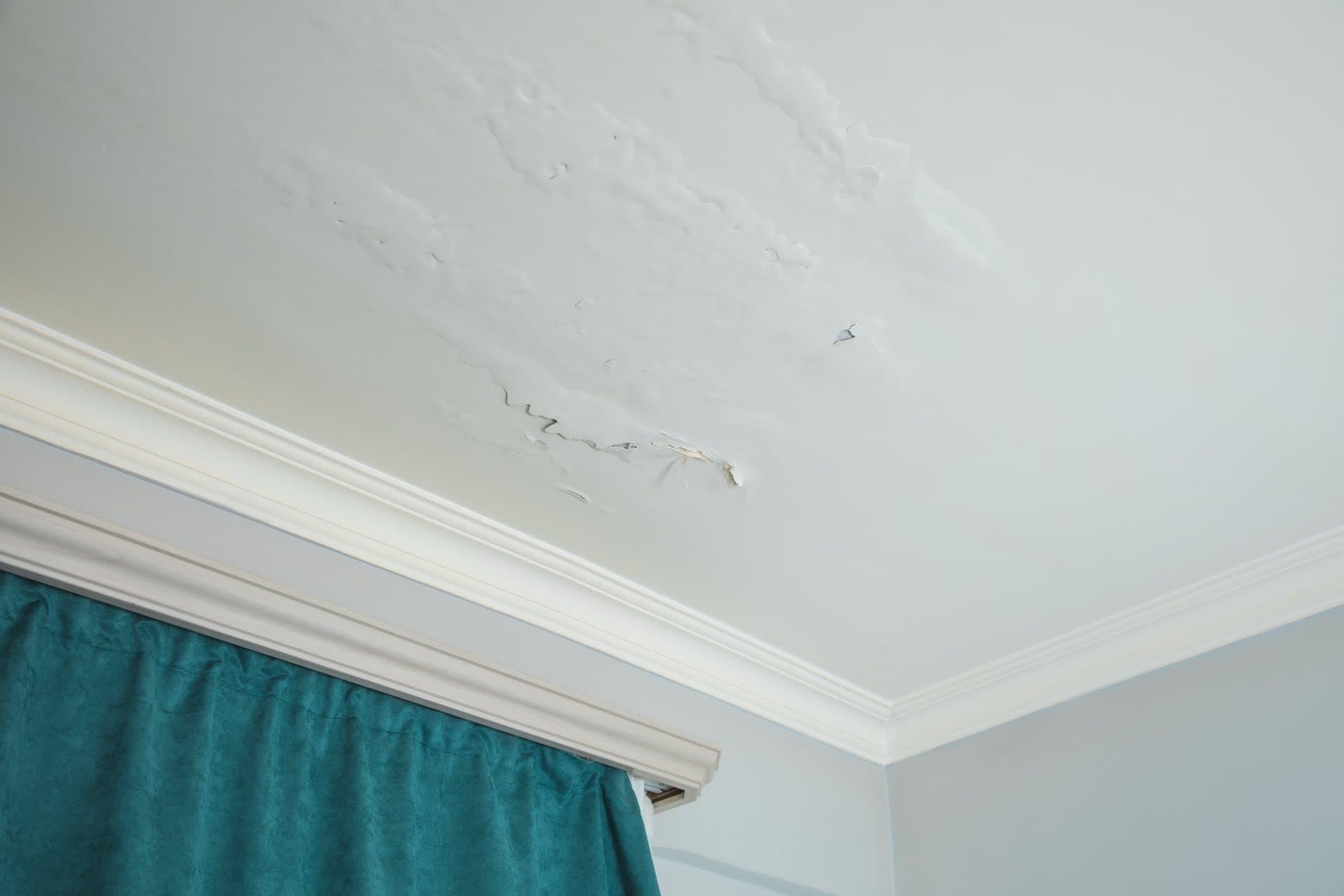 Roof and Balcony Leak Detection in Dubai: Cracked and peeling plaster on a ceiling below a roof