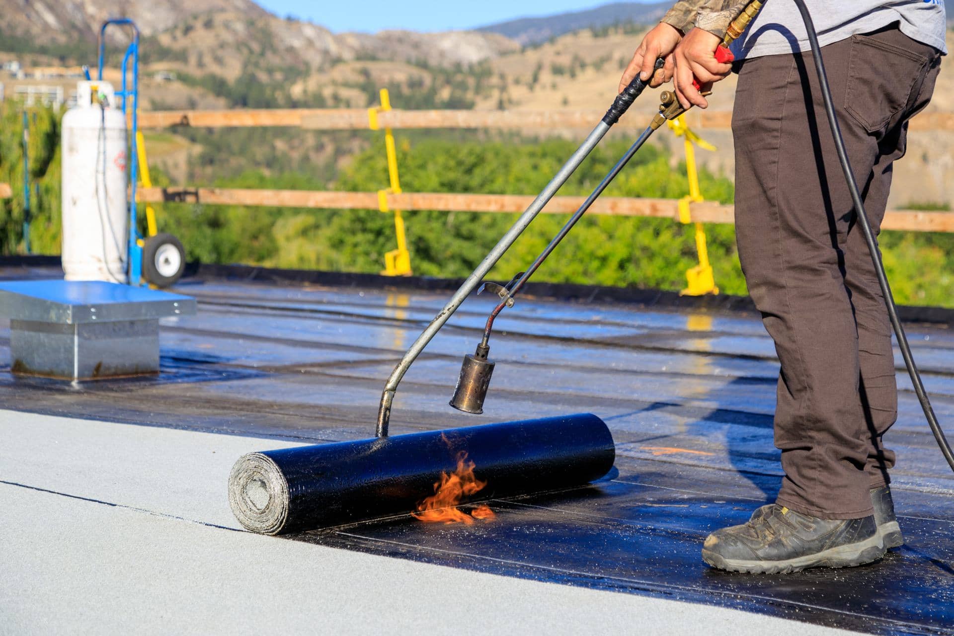 Worker torch-applying a bitumen waterproofing membrane on a roof in Dubai