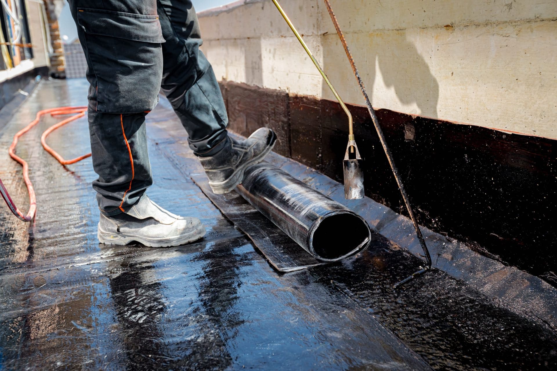 Roof Waterproofing in Dubai: Roofer unrolling a waterproofing membrane on a flat roof