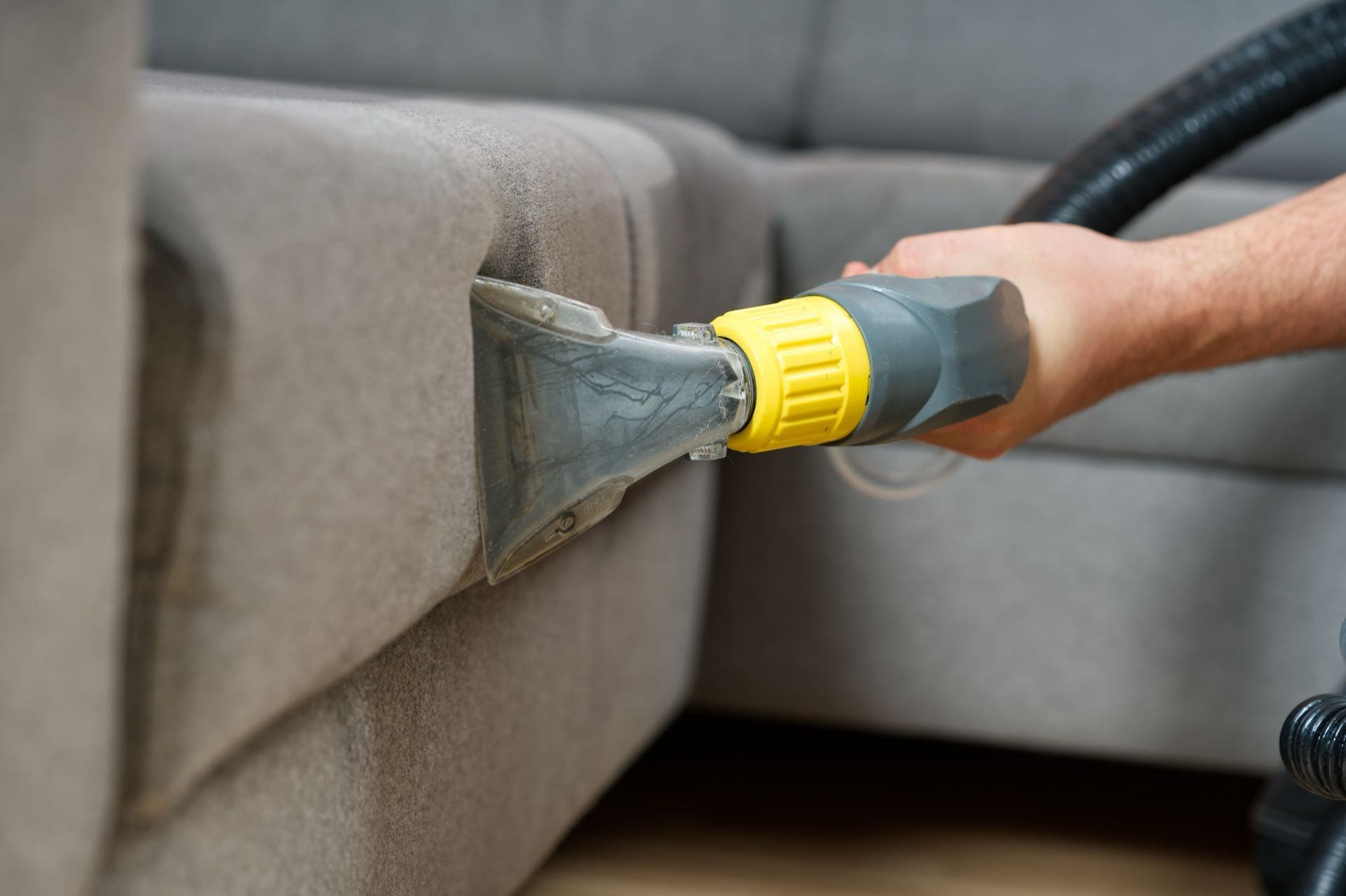 Sofa Cleaning in Dubai: Extraction cleaning head being used on a grey fabric sofa