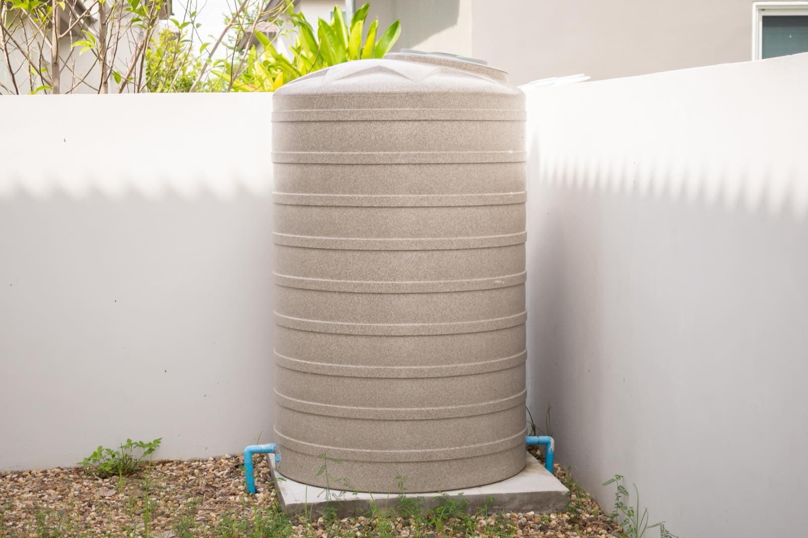 Villa Water Tank Cleaning in Dubai: Beige water storage tank beside a villa wall with pipework