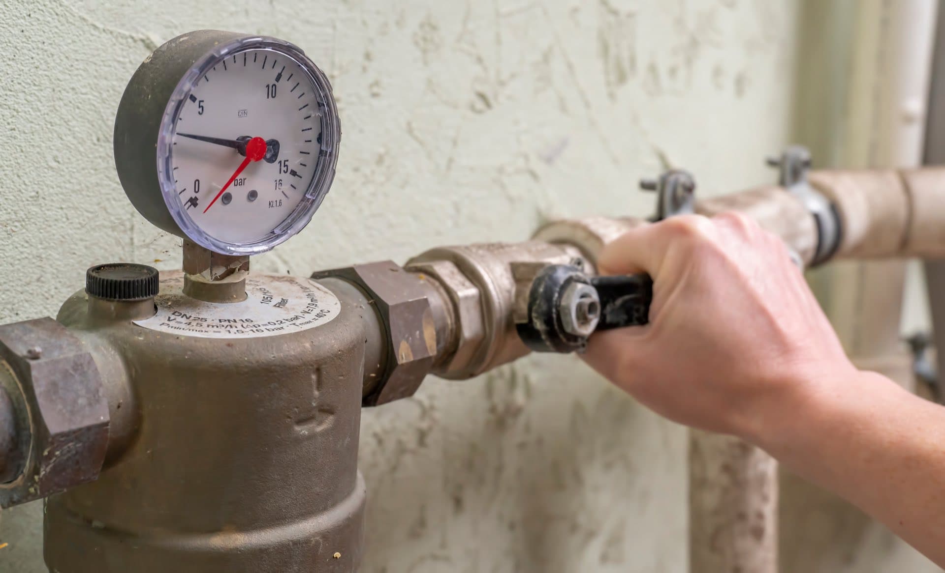Water Pressure Correction in Dubai: Hand adjusting a valve beside a water pressure gauge