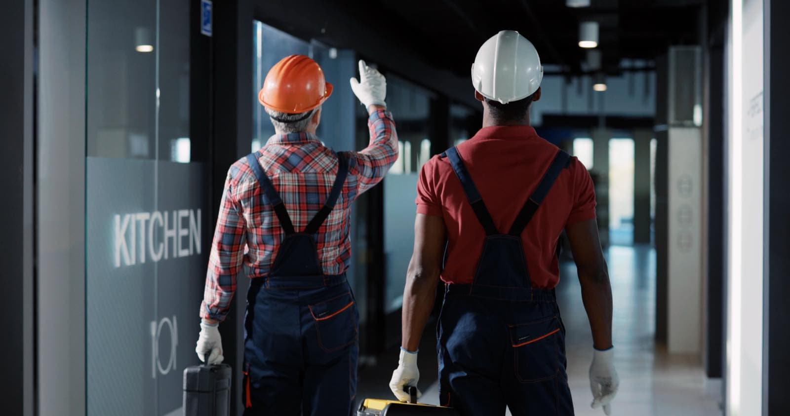 Multi-Floor Coordination in Dubai: Two workers in hard hats walking along an office corridor